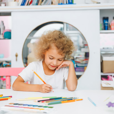 Cute little blonde preschooler girl draws at home